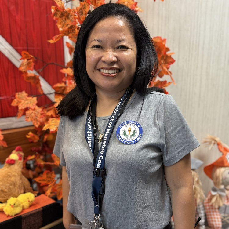 A school district employee standing in front of a fall decorated lobby