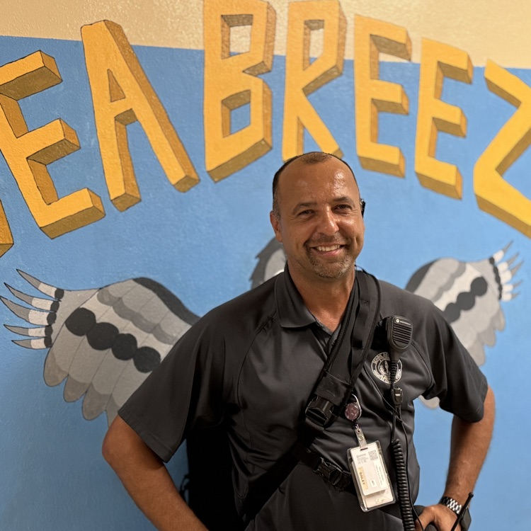 A school safety guard stands in front of a colorful mural
