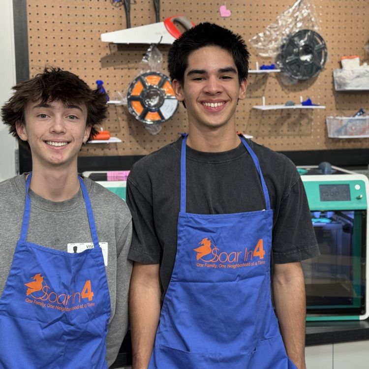 Two teen volunteers wearing blue aprons in a new children’s learning museum, The Soar Lab