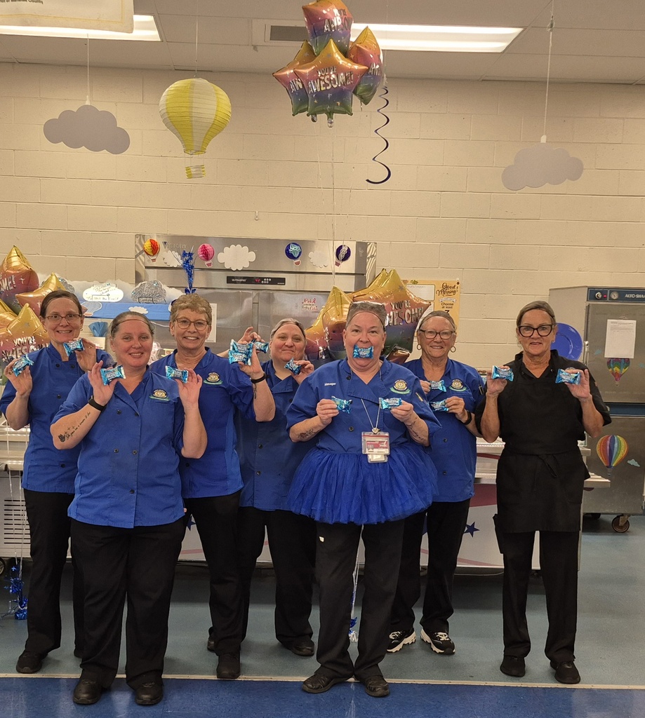 A cafeteria team wearing blue and holding rice crispy treats.