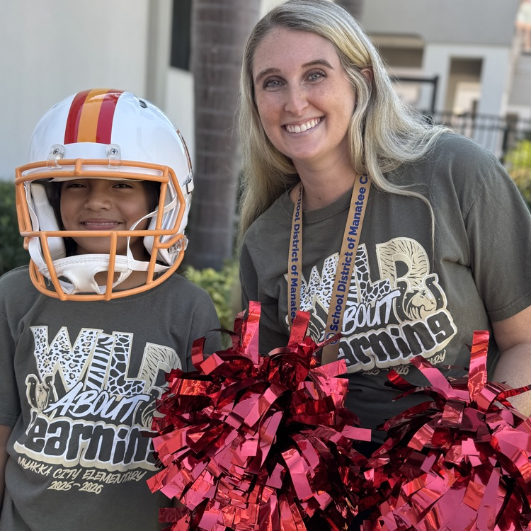 A teacher holding pom-poms with a student wearing a buccaneers football helmet
