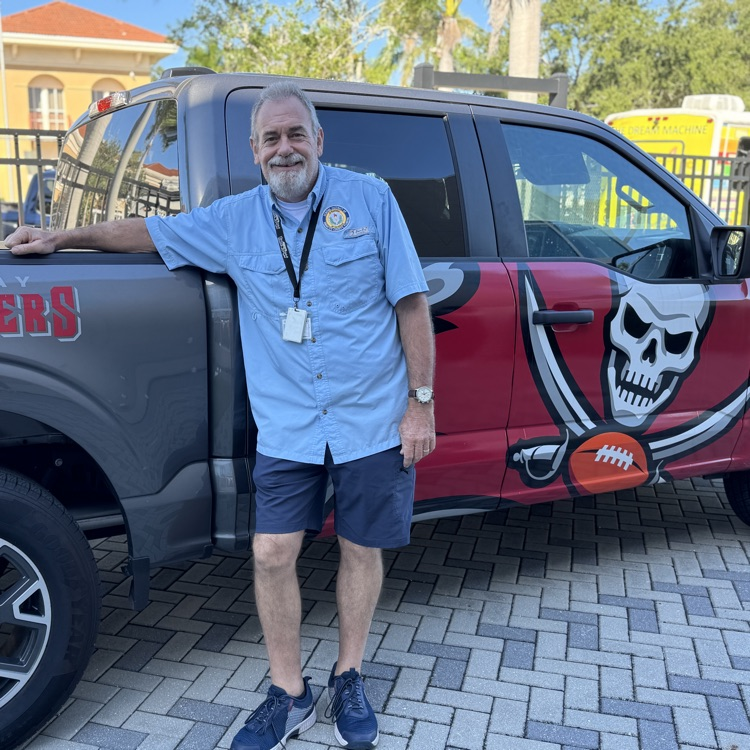 A school bus driver and teacher leans up against a truck owned by the Tampa Bay Buccaneers