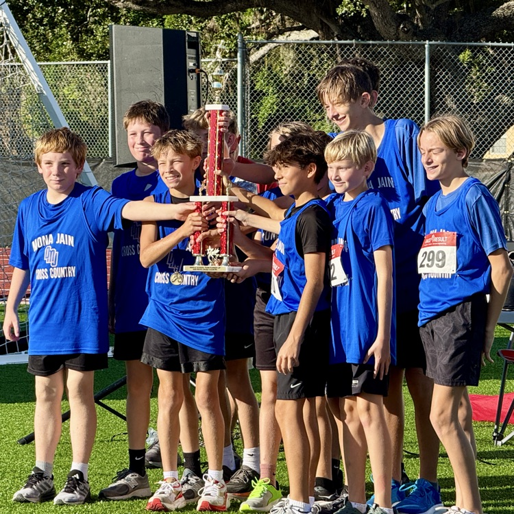 Middle school runners hold up a trophy