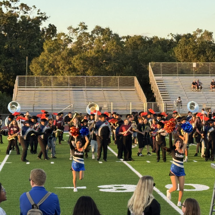 middle school musicians join high school marching band performers during a Friday night football game