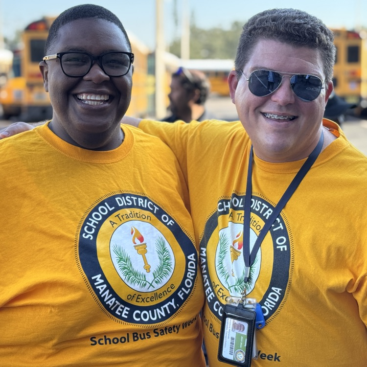 two transportation employees wearing bright, yellow shirts, and smiles
