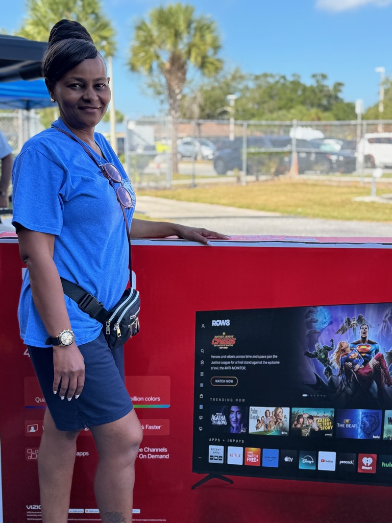 A dedicated district employee stands with her raffle prize, a 65" smart tv