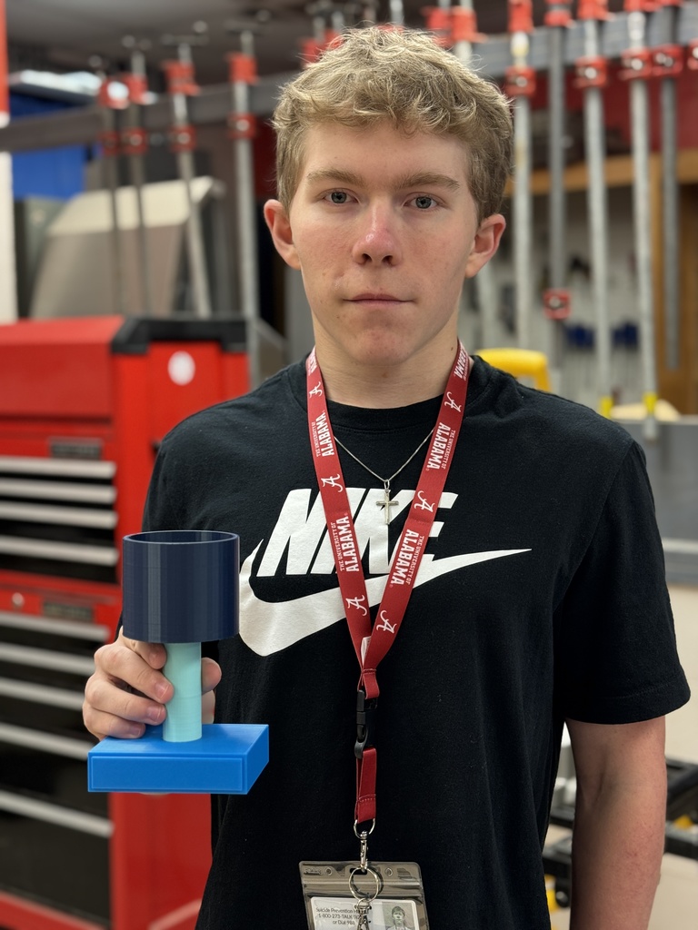 A teen holds up his 3D printed trophy prototype