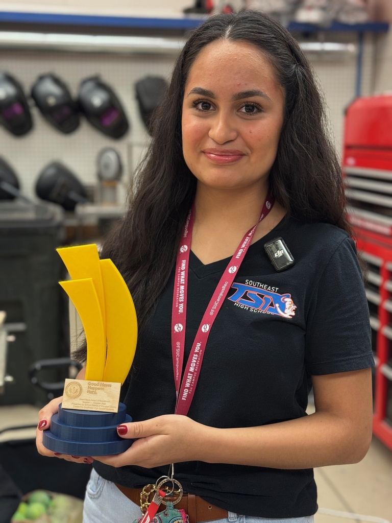 A young woman holds a 3D printed trophy with a Good News Happens Here logo