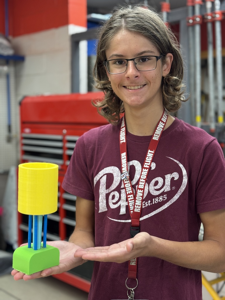 A teen holding up the 3D print of his trophy prototype