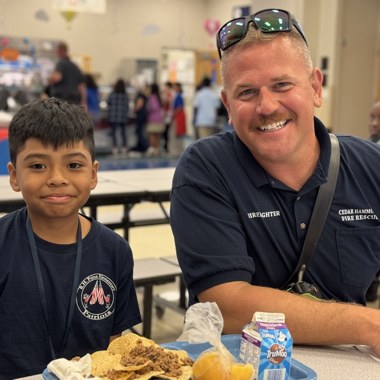 A first responder and a student smile in the school cafeteria
