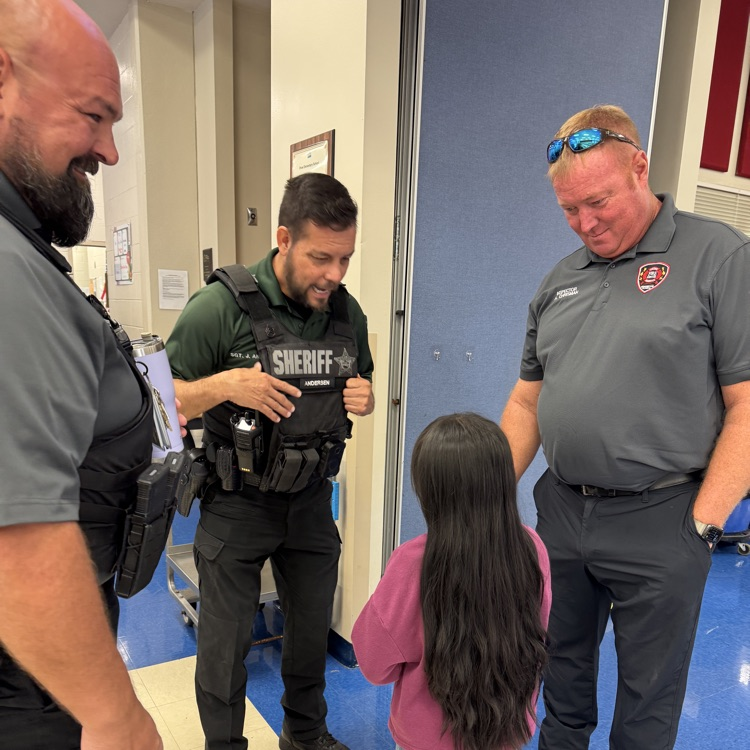 A young girl asks her school safety guardian to introduce her to visiting first responders