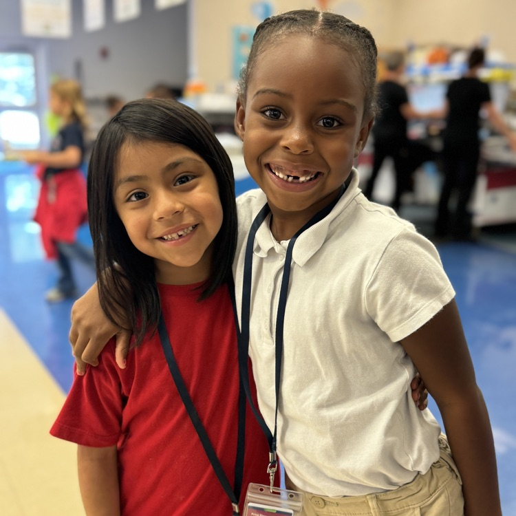 A pair of young girls smiling in the school cafeteria