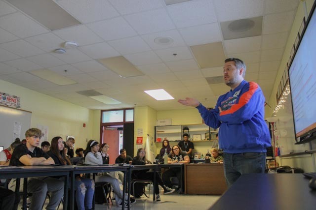 A professor from University of Florida speaks to high school students about a journalism program.