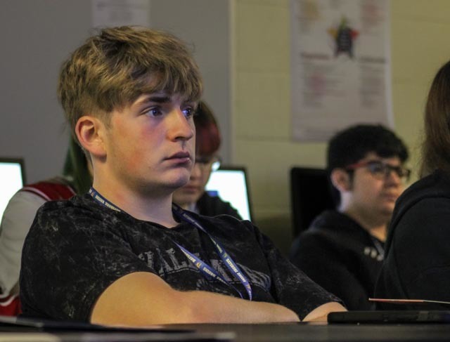 A journalism student listens to a special guest speaker in class.