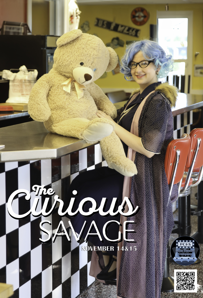 A teenager stands in a diner holding a large teddy bear with the words, The Curious Savage.