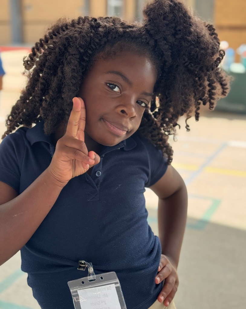 A child wearing a blue polo shirt holds up a peace sign.
