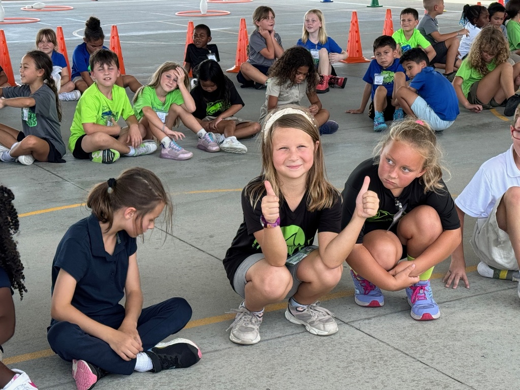 A young girl gives two thumbs up while squatting down