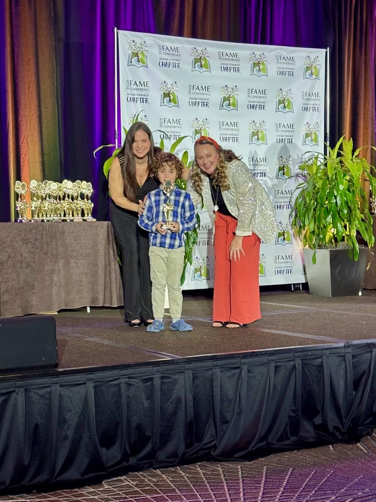 A student holding a trophy on stage.