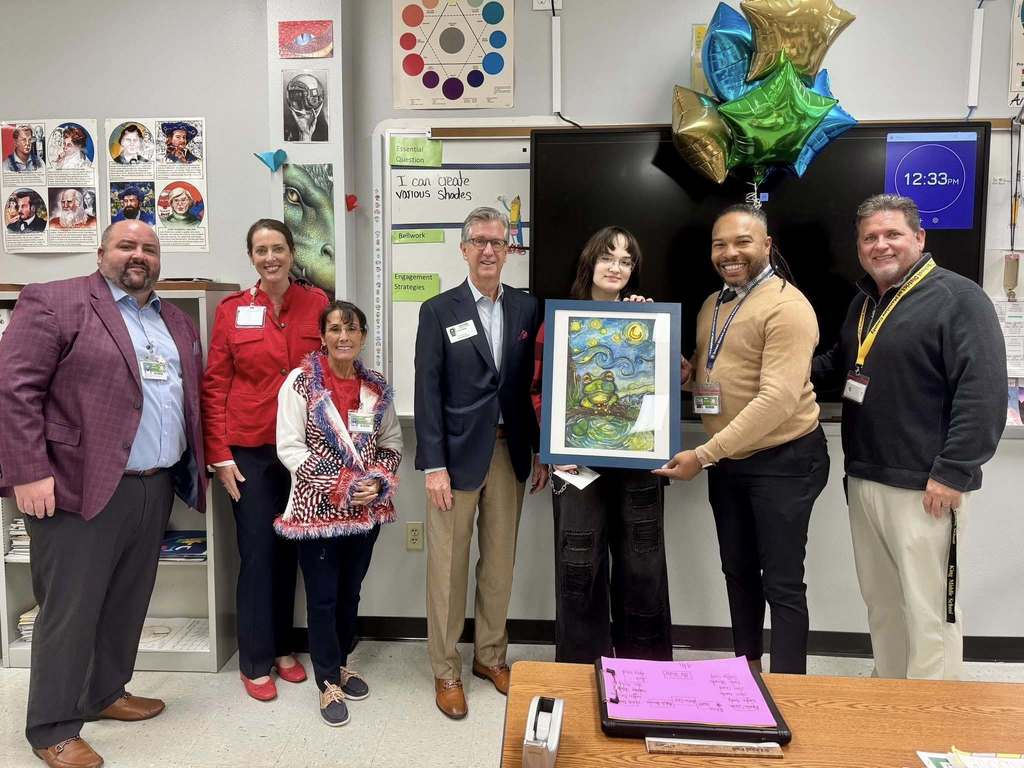 A group of school district officials congratulate a young artist whose work will hang in Tallahassee.