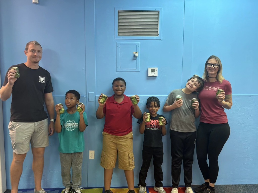 Students smiling while holding their jarred pickles.