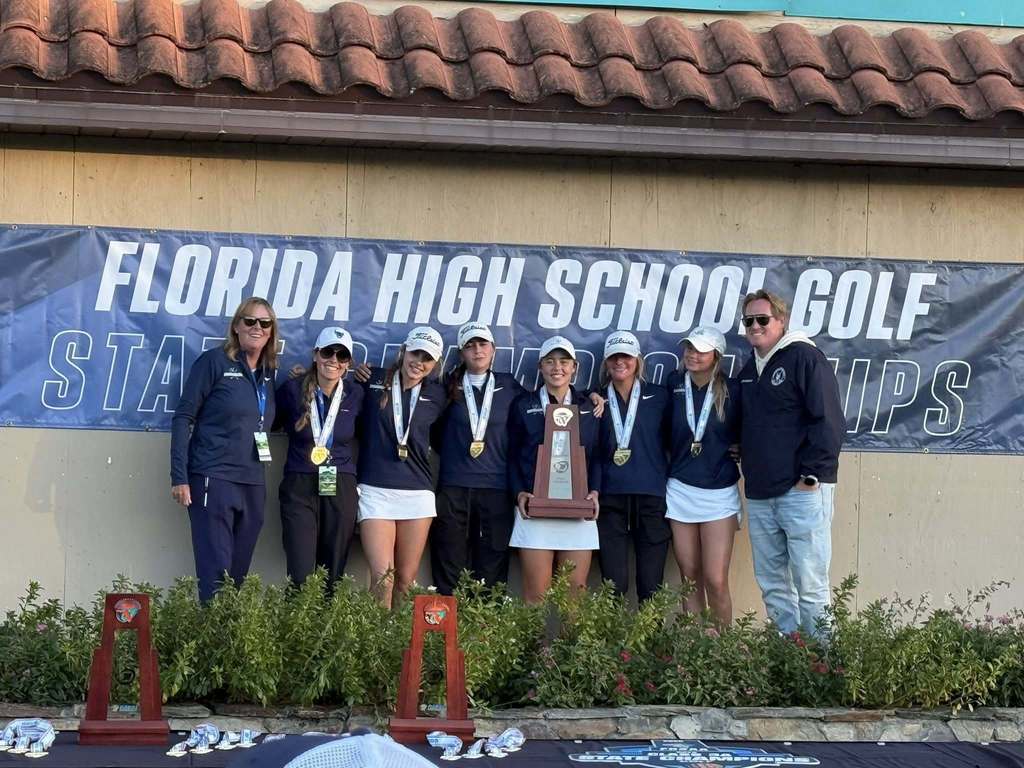 Girls golf team and their coaches holding a first place state trophy.