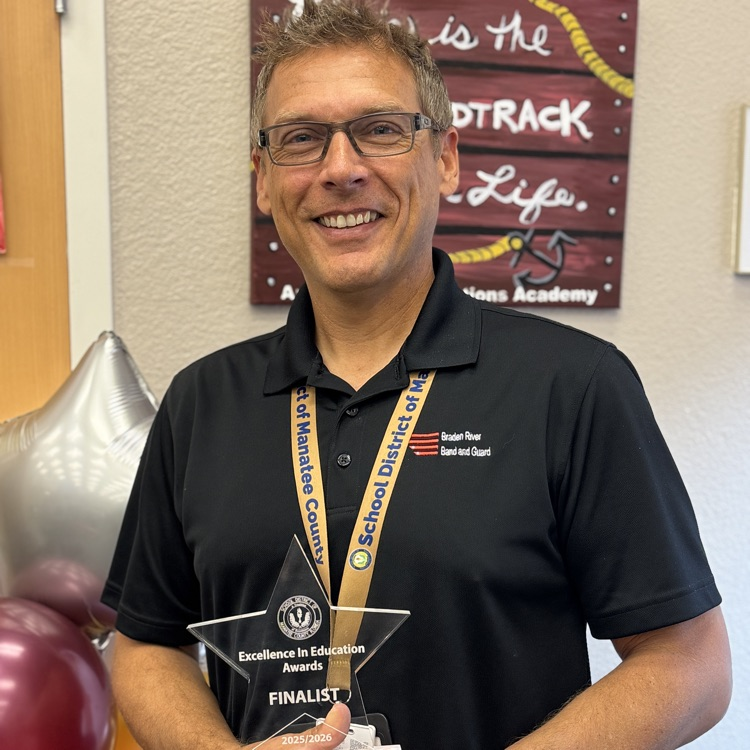 A teacher of the year, final smiling while holding his trophy