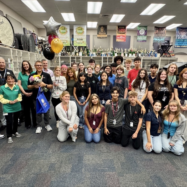 A band class celebrating their high school music teacher after he was surprised with the teacher of the year finalist