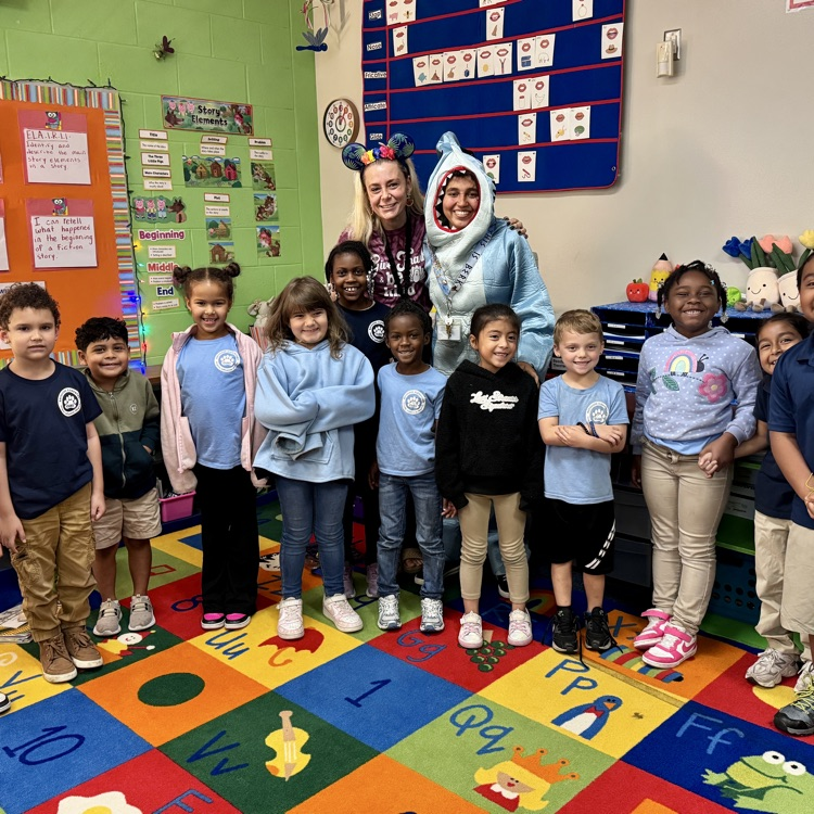 A teacher, paraprofessional, and class of students, smiling