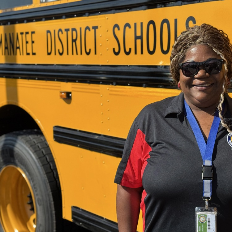 A school bus driver standing outside of her bus