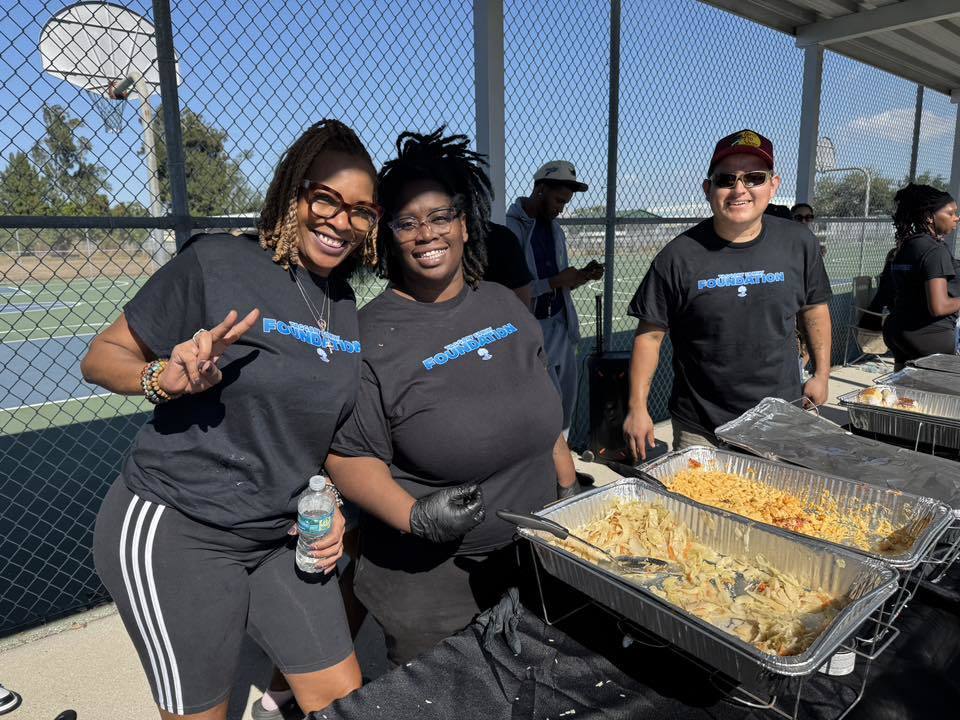 Volunteers smiling while passing out food to the community.