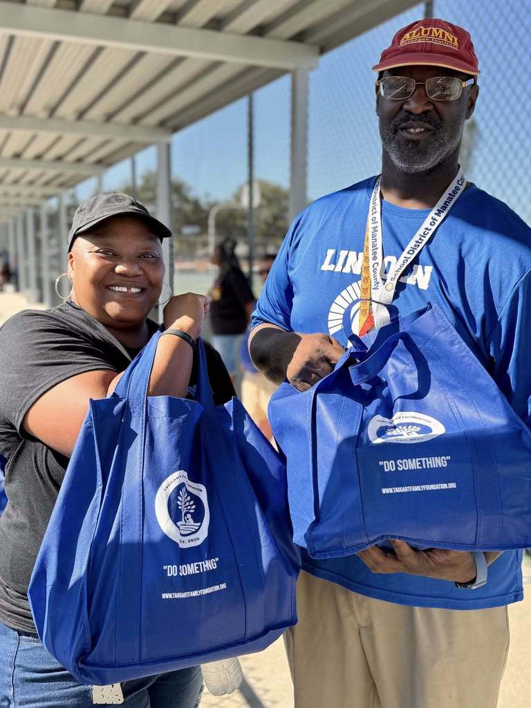 A school administrator and volunteer hand out bags of food to families for Thanksgiving