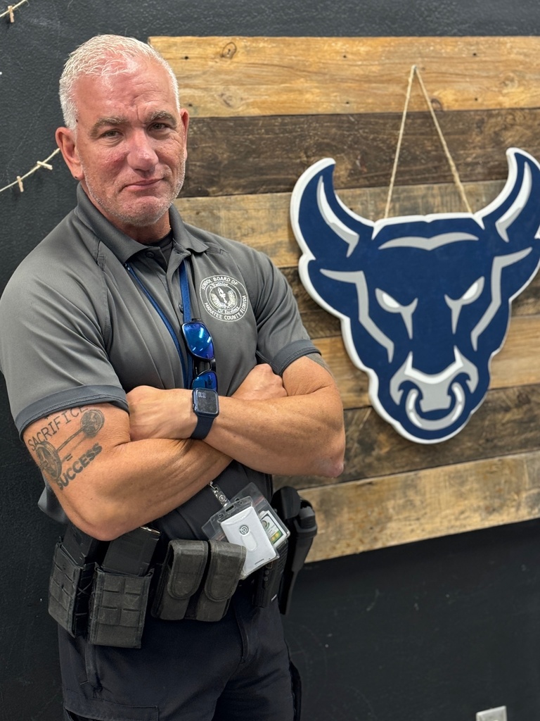 A school safety guardian stands next to a wall with the school Bulls logo