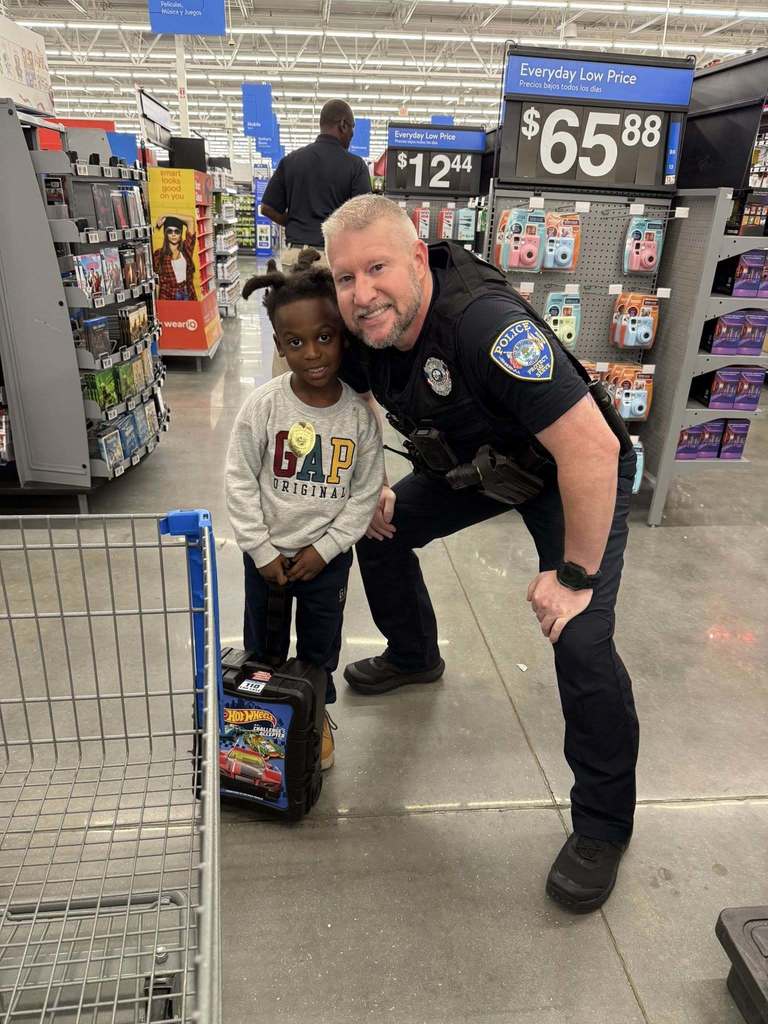 a police officer leans down to take a photo with a young boy who is shopping for christmas.