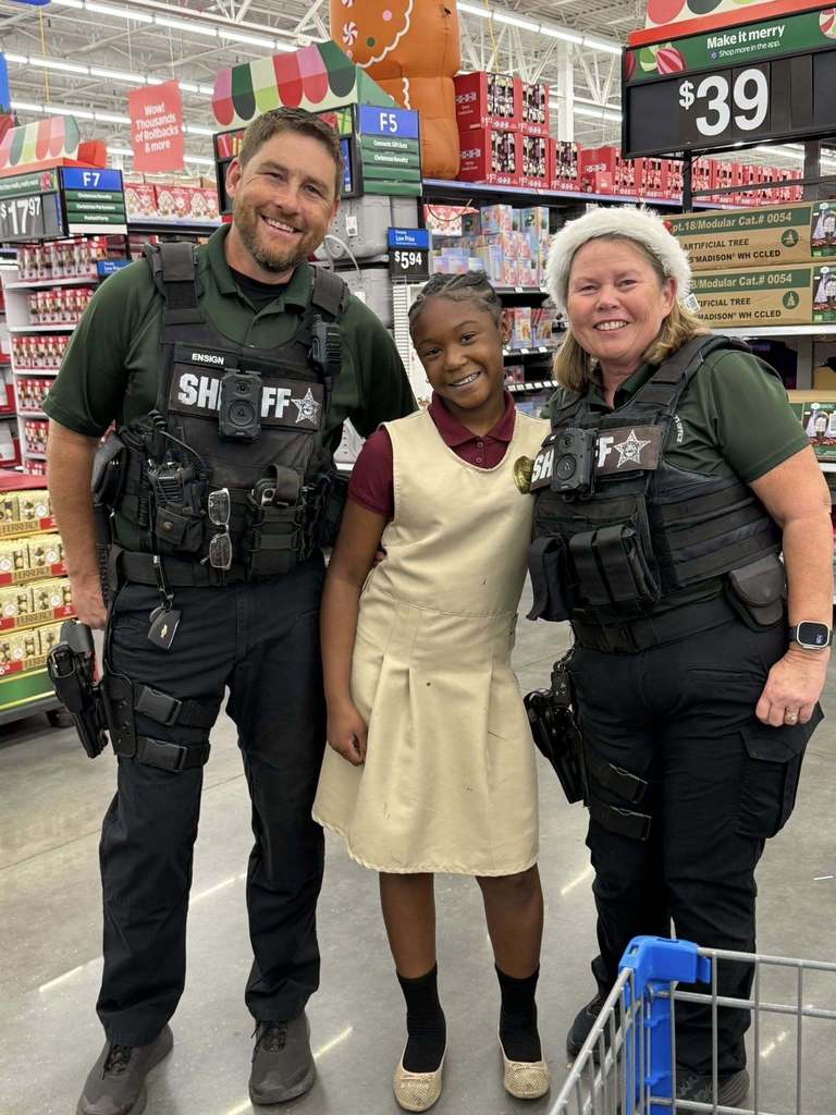 two sheriff's deputies take a young lady shopping for christmas.