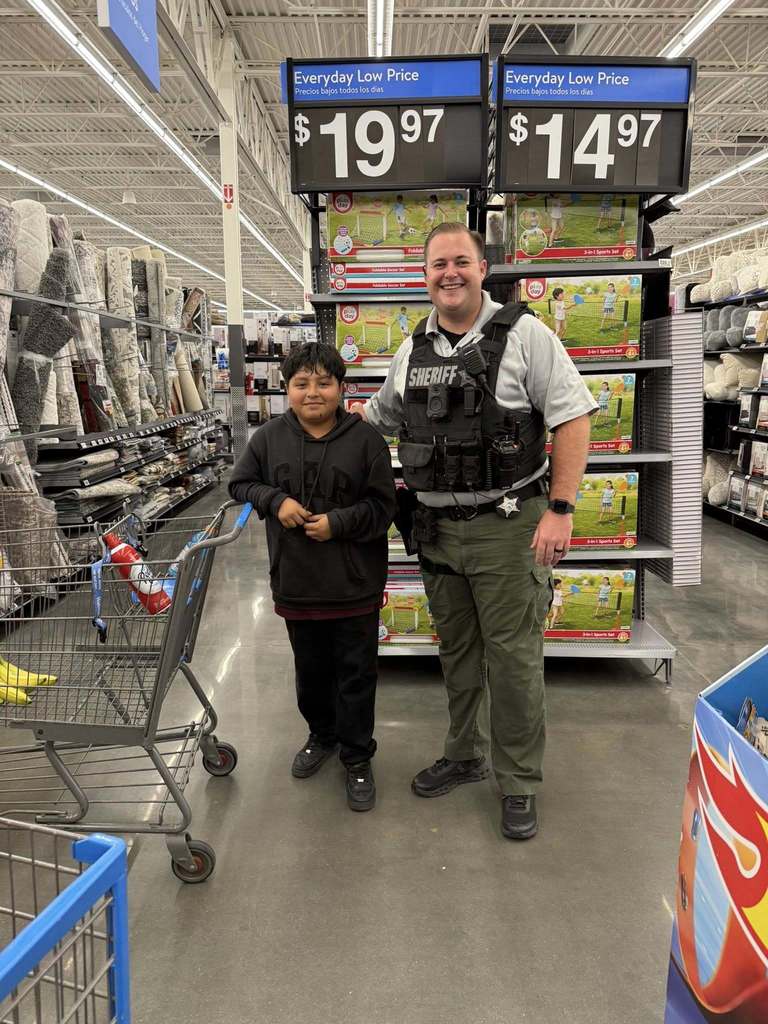 a sheriff's deputy takes a young boy shopping for christmas.
