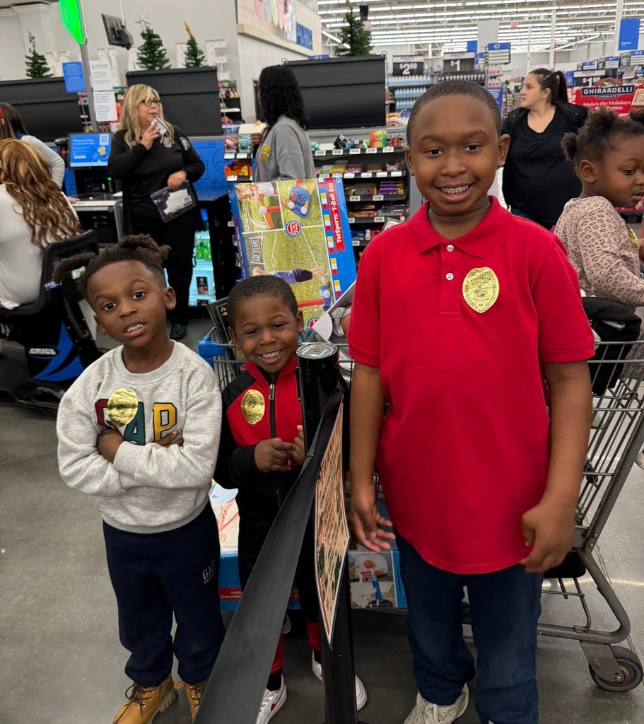 three smiling kids wearing gold sticker "badges" go shopping with deputies for christmas.