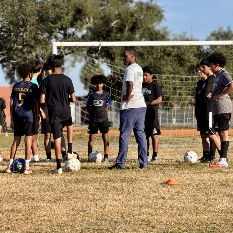 Soccer players gathered in a circle on the field