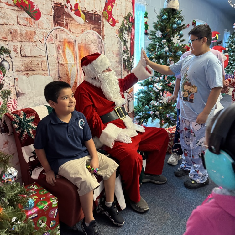two kids sitting with Santa in the chief elf