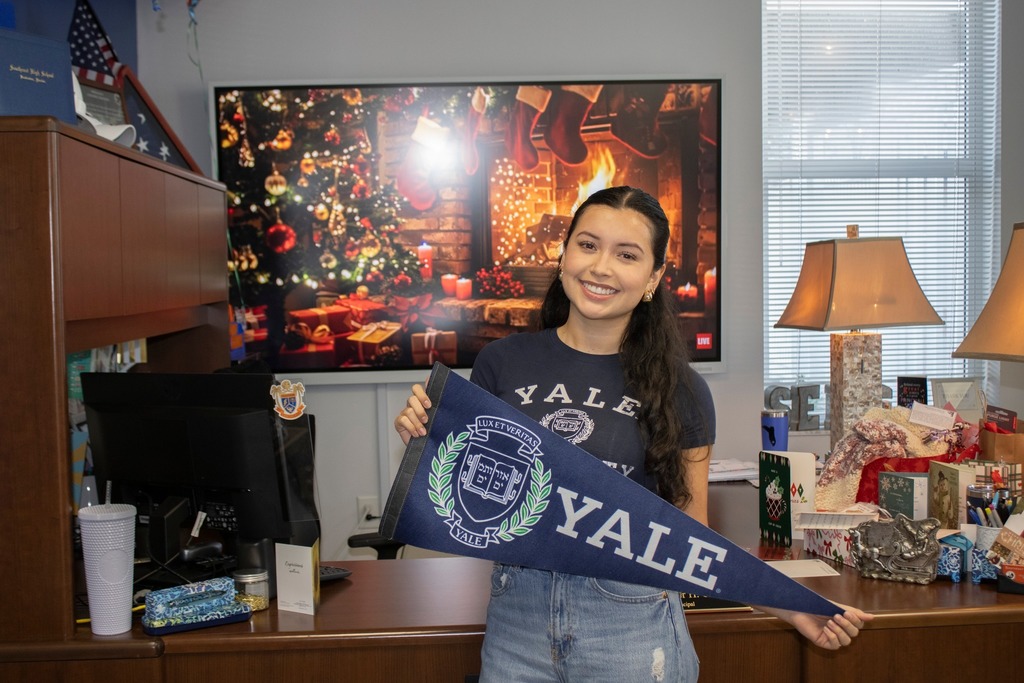 A high school student holding a Yale pennant after receiving notification of her acceptance.
