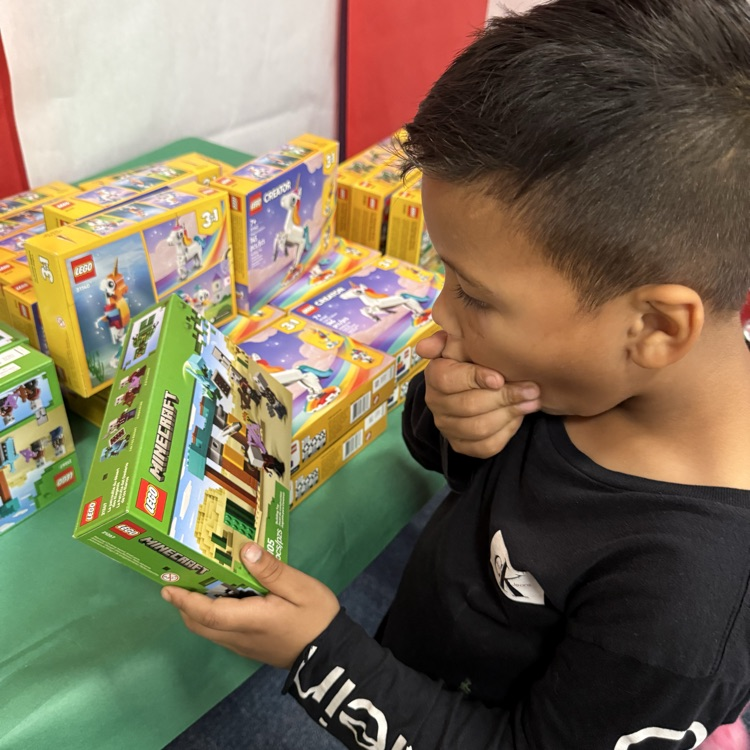 A boy with a hand over his mouth, shocked at the toy just received
