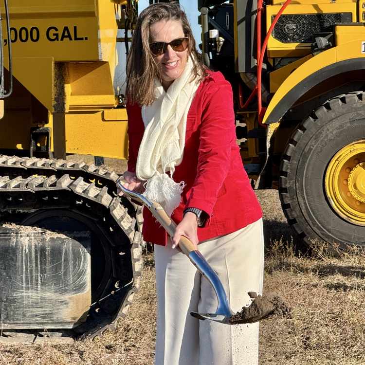 superintendent of schools lifts a shovel filled with dirt