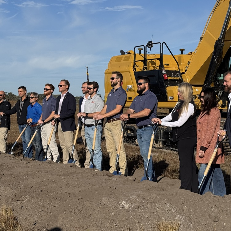 A group of builders stands at a sight where a high school will be built