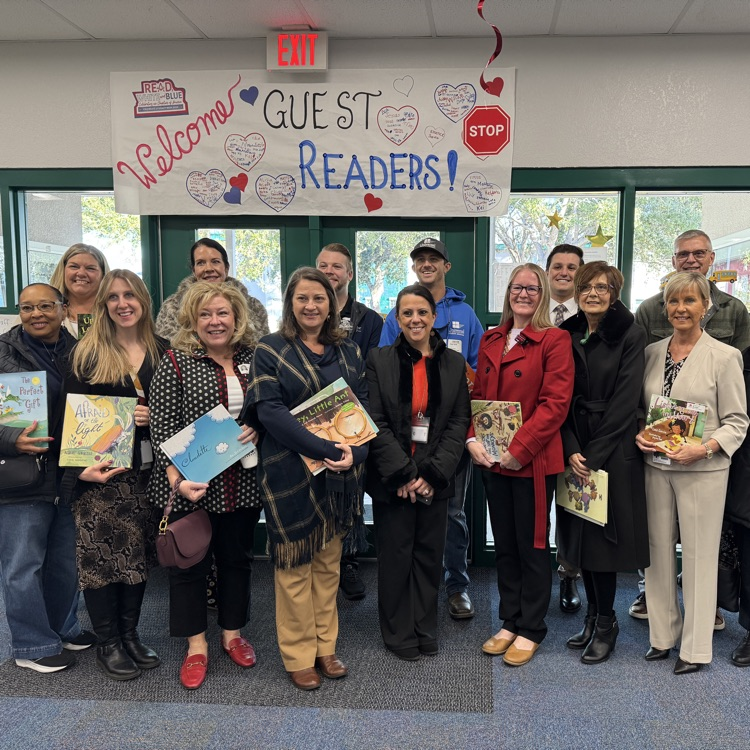 A group of adults with books in their arms, getting ready to read to students