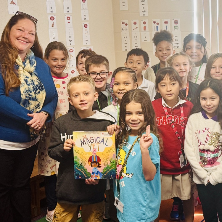 A guest reader smiles with students in a classroom