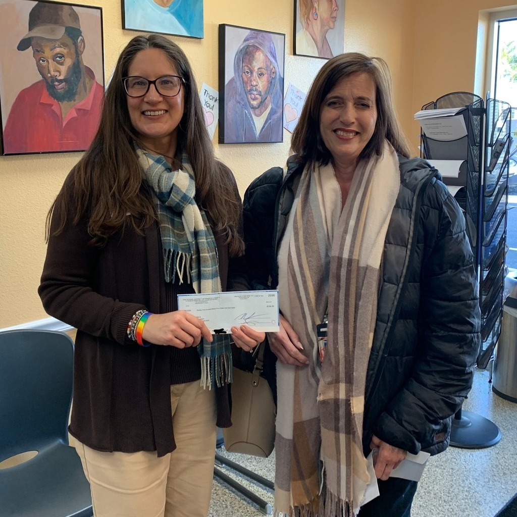 Two women smiling and one holding a check.
