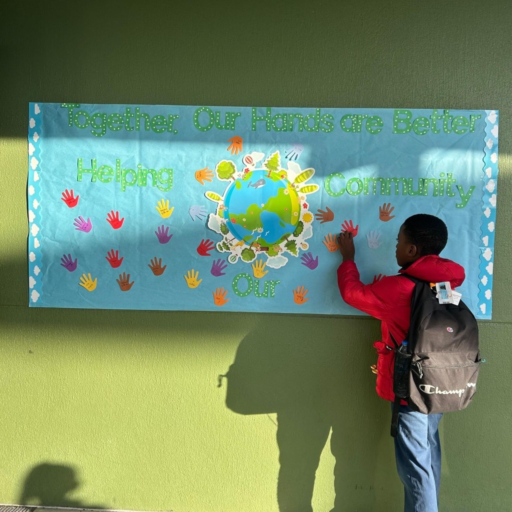 A boy touching a banner with children's hands on display.