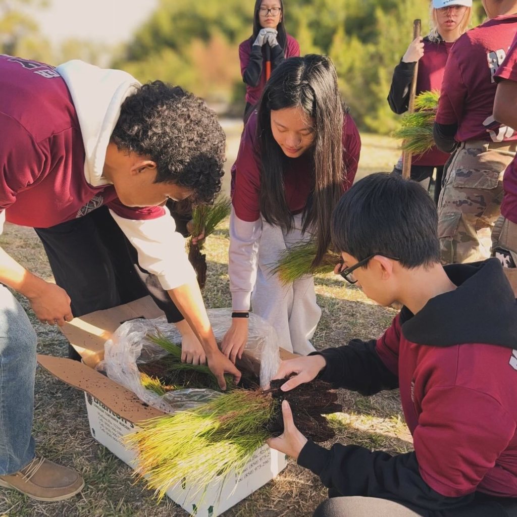 Students gathered in a circle unboxing tree saplings.