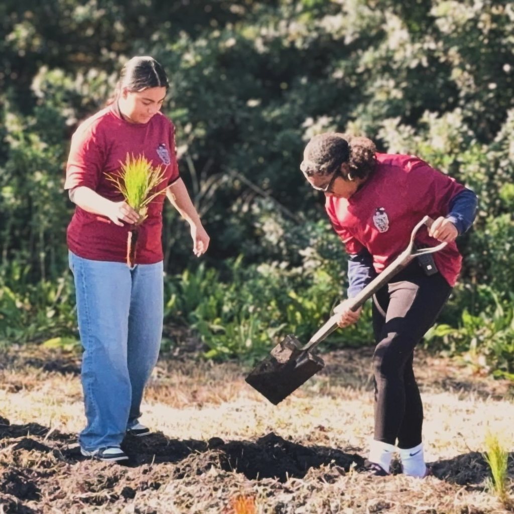 Two students digging a hole outdoors.