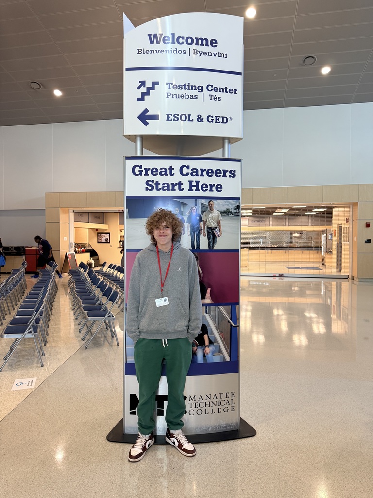 A high school students stands in front of a sign which reads, "Great Careers Start Here".