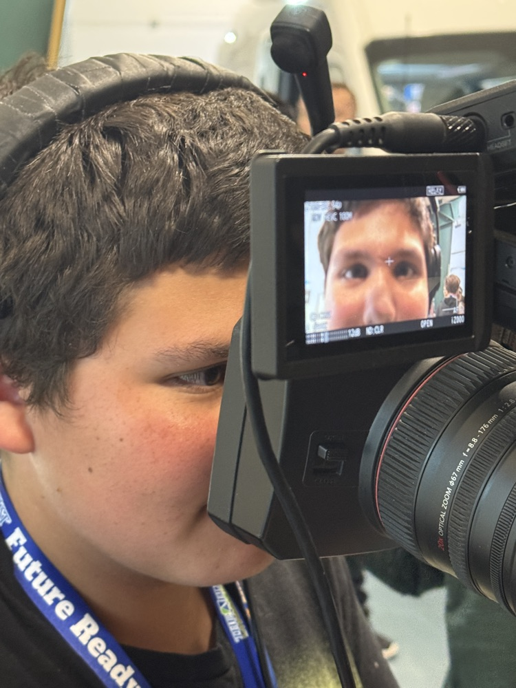 A student puts his face in the lens of a television camera